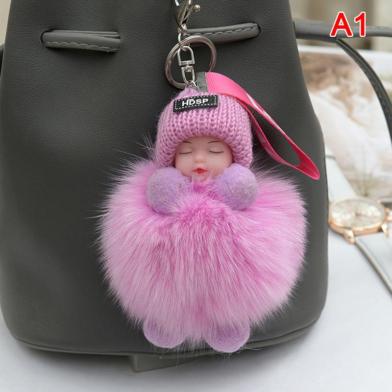 Schlüsselanhänger mit Bommel und schlafendem Baby. Niedliche, flauschige Plüschpuppen-Schlüsselanhänger